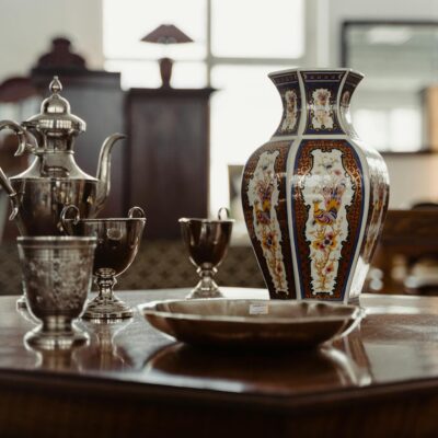 A collection of antique metalware and ceramics on a wooden table, capturing a vintage aesthetic.