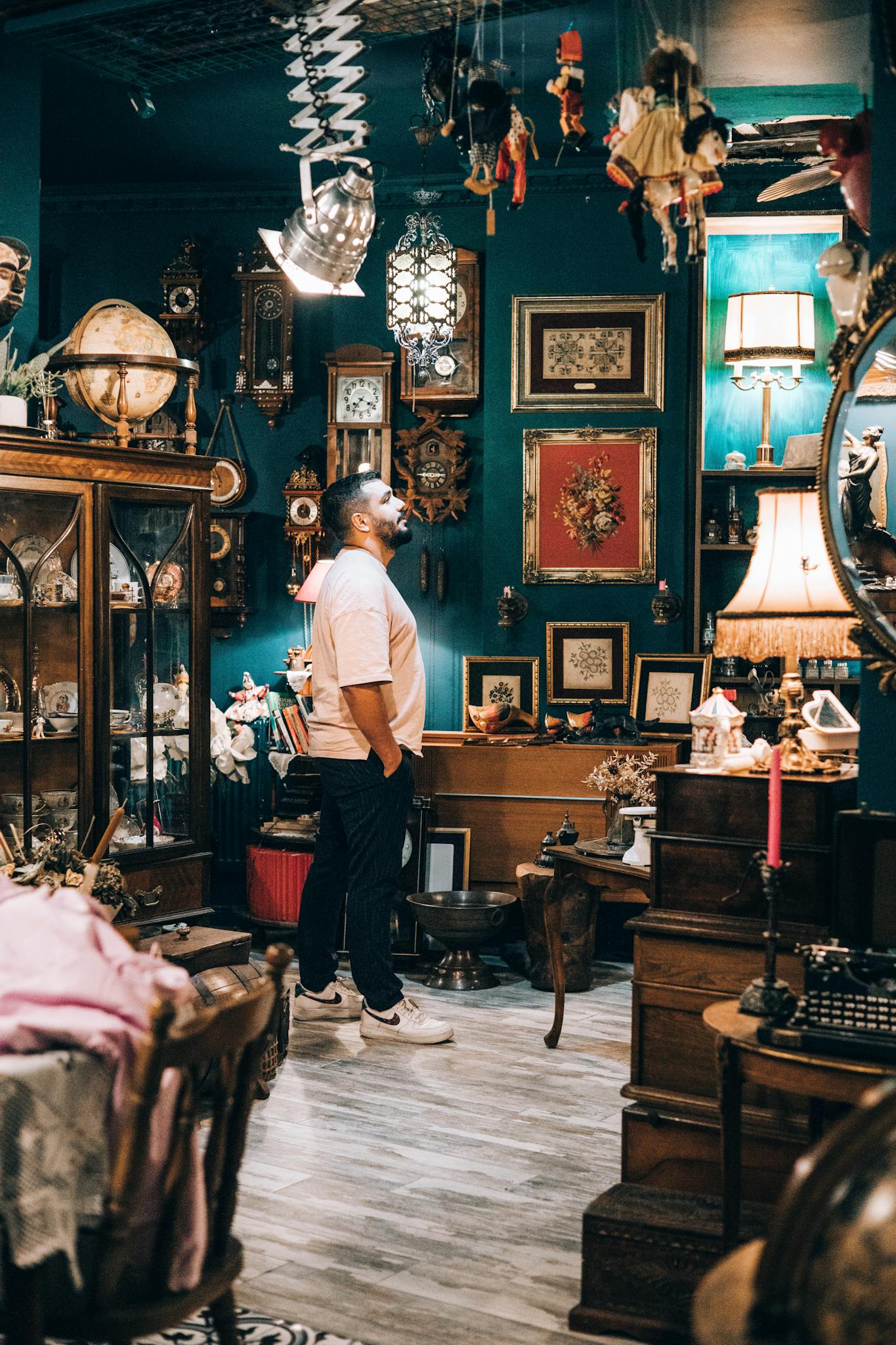 A man standing and exploring a vintage antique shop filled with unique decor items.